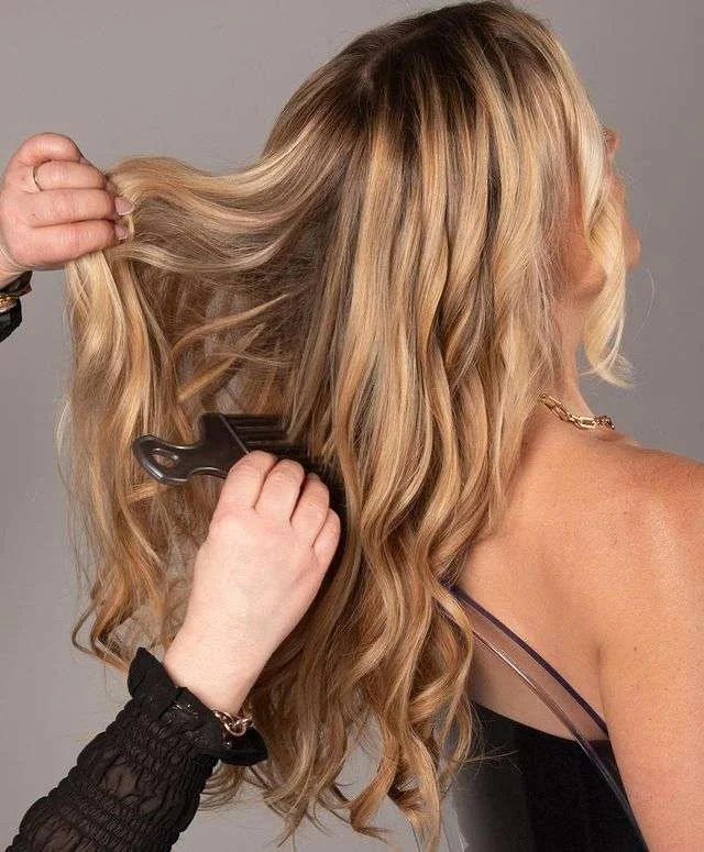 Penny styling a client's wavy blonde highlighted hair
